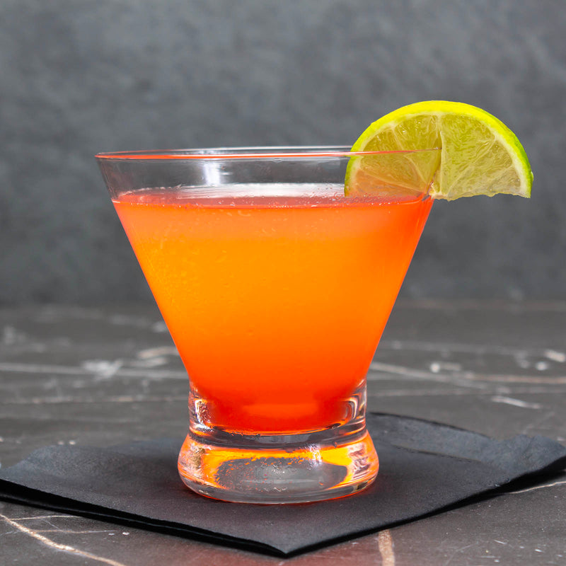 Cocktail with a lime wedge on a dark surface