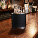 Black leather flask on a bar counter with blurred bar background