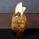 Glasses of a festive drink with apple slices and star anise, featuring 'Cheers to the New Year' text.
