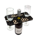 Wine bottle and glasses on a decorative stand with 'New Year's Eve' theme