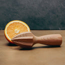 Wooden orange squeezer with a halved orange on a wooden surface