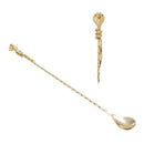 A gold-toned metal bar spoon with a long twisted handle and a decorative cobra-head end, shown on a plain white background with a smaller inset view of the top detail.