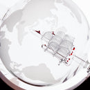 A close-up of a clear glass globe with a white world map design and a transparent ship ornament inside, set against a bright white background.