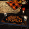 Halloween-themed decor with 'Trick or Treat' mat, candles, and fall elements on hay.