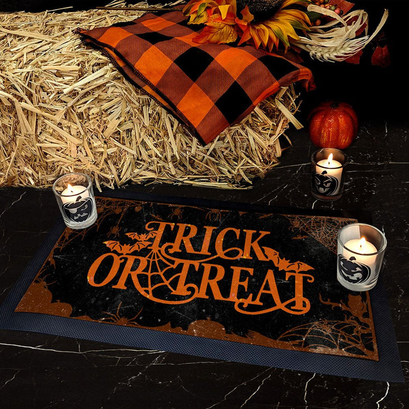 Halloween-themed decor with 'Trick or Treat' mat, candles, and fall elements on hay.