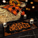 Halloween-themed decor with hay bale, checkered cloth, sunflower, pumpkins, and 'Trick or Treat' sign.