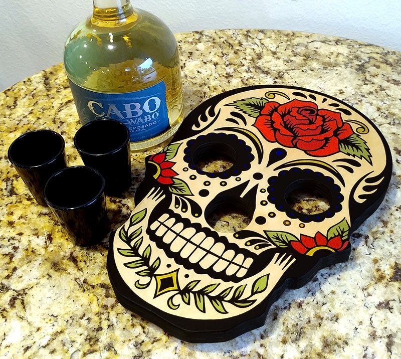 Decorative skull-shaped tray with shot glasses and a bottle of Cabo Wabo tequila on a granite surface.