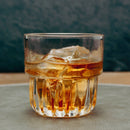 Glass of whiskey with ice cubes on a textured surface