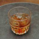 Glass of whiskey with ice cubes on a textured surface